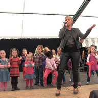 Danielle auf der Bühne mit einer Kindergruppe im Hintergrund